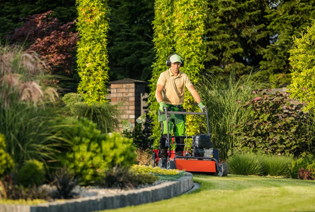 Landscaper with a lawnmower in a beautiful garden